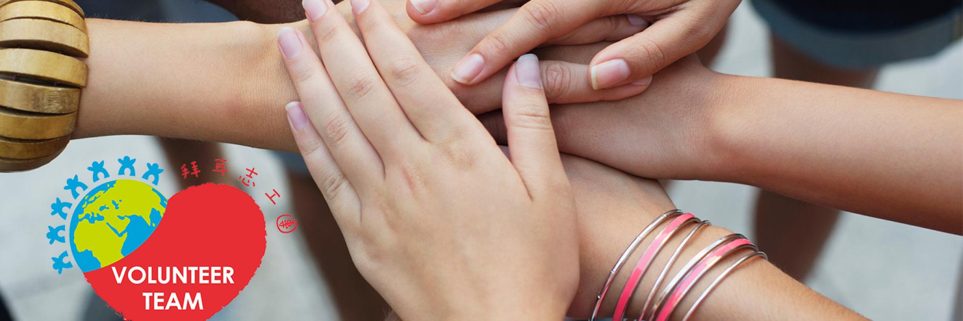 A group of diverse hands joined together above a "Volunteer Team" logo with a heart and globe design.