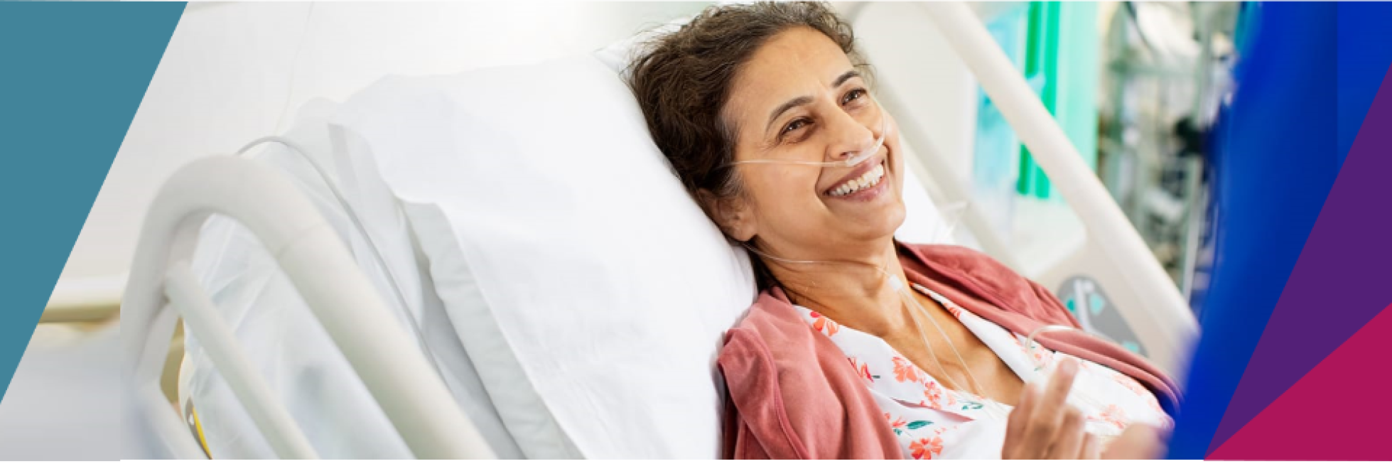 A woman in a hospital bed, smiling while wearing a nasal cannula.